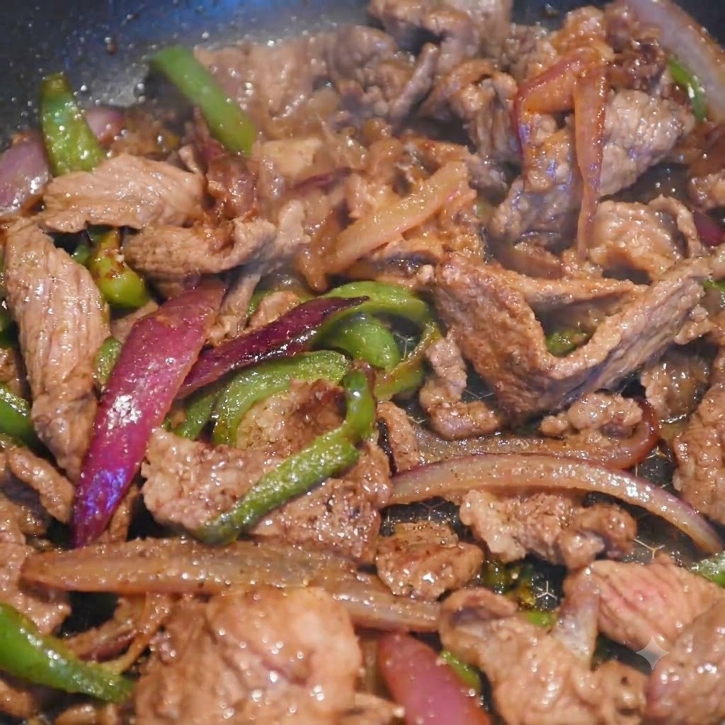 Rindfleisch und bunte Gemüsestreifen garen zusammen in einer Pfanne, während Gewürze hinzugefügt werden.