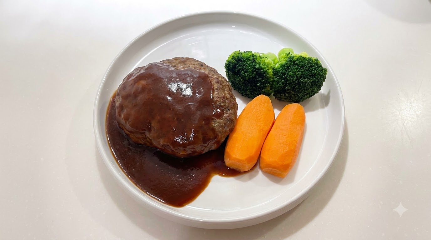 Ein saftiges japanisches Hambagu-Steak, überzogen mit einer glänzenden dunklen Sauce, serviert mit Karotten und Brokkoli.