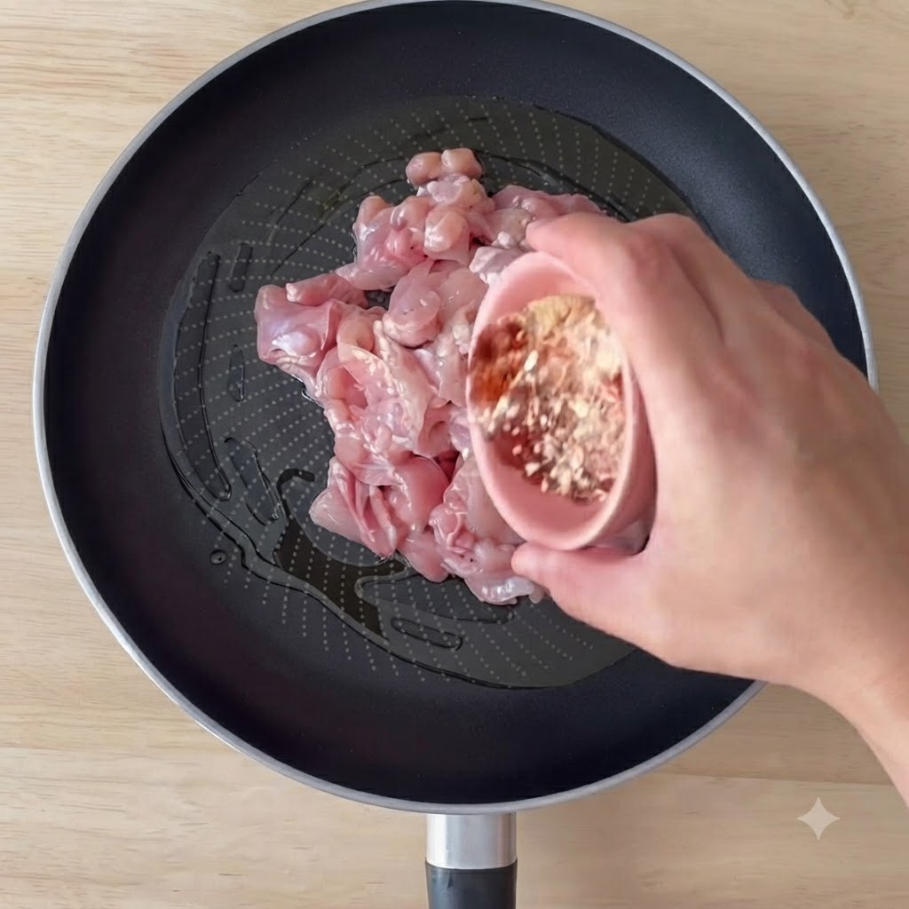 Hähnchenstücke in einer Pfanne mit Olivenöl und Gewürzen werden angebraten und umgerührt.