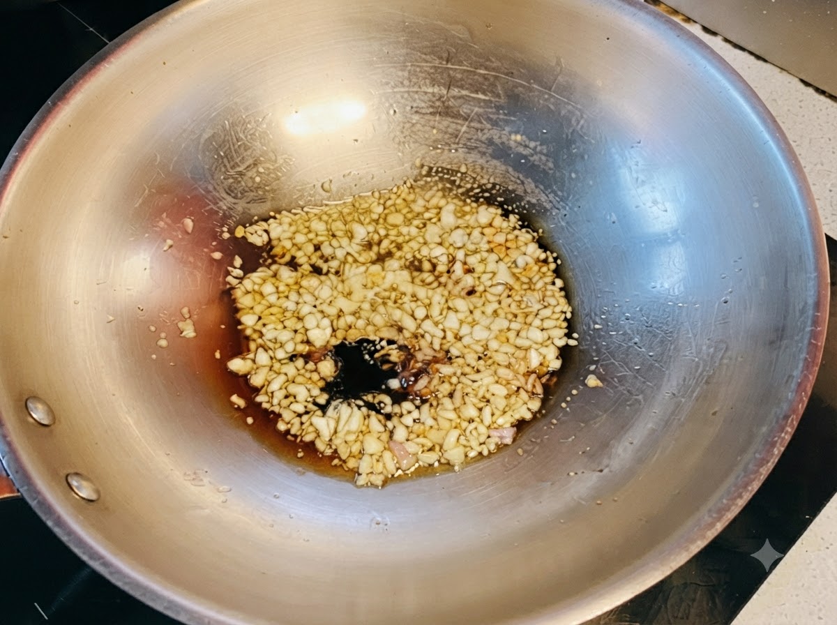 Dunkle und helle Sojasaucen kombiniert mit Honig sprudeln über angebratenem Knoblauch im Wok.